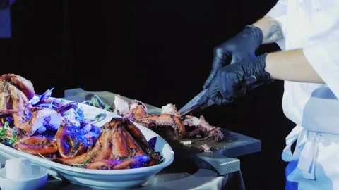 The chef cuts the cooked octopuses into portions and puts them on a plate. Stock Footage 169235579