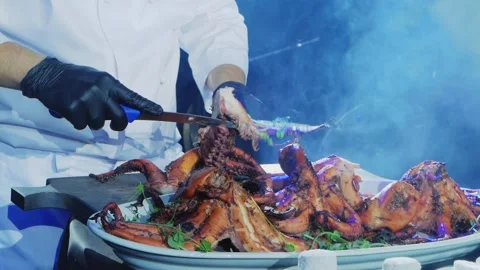 The chef cuts the cooked octopuses into portions and puts them on a plate. Stock Footage 169410857