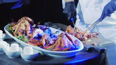 The chef cuts the cooked octopuses into portions and puts them on a plate. Stock Footage 169526772