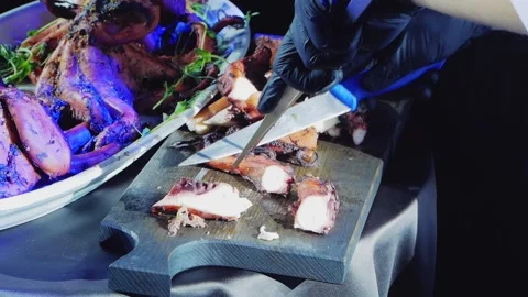 The chef cuts the cooked octopuses into portions and puts them on a plate. Stock Footage 169652051