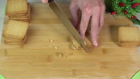 Chef cuts cookies with a kitchen knife to prepare dessert. Cookie crumbling. Stock Footage 241462165