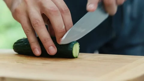 The chef cuts a cucumber with a hand knife close-up Stock Footage 130992201