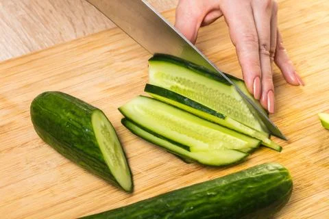 Chef cuts cucumber with a knife Stock Photos