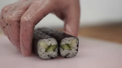 The chef cuts the cucumber rolls with a knife into eight pieces Stock Footage 106670554