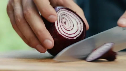 The chef cuts off the edges of a red onion close up of a hand and a knife Stock Footage 130790650