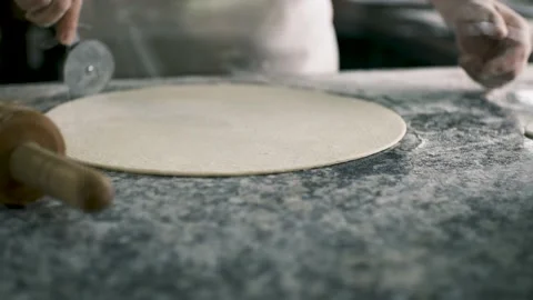 The chef cuts the edges of the round-shaped dough with a special roller.View Stock Footage 199214787