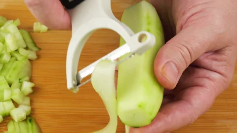 A chef cuts a fresh green cucumber into thin slices. 库存影片 342285592
