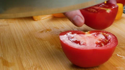Chef cuts fresh red tomato into slices on a wooden cutting board. Stock Footage 341506504