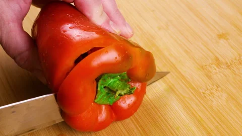 A chef cuts a fresh sweet red bell pepper on a wooden board.  库存影片 341515665