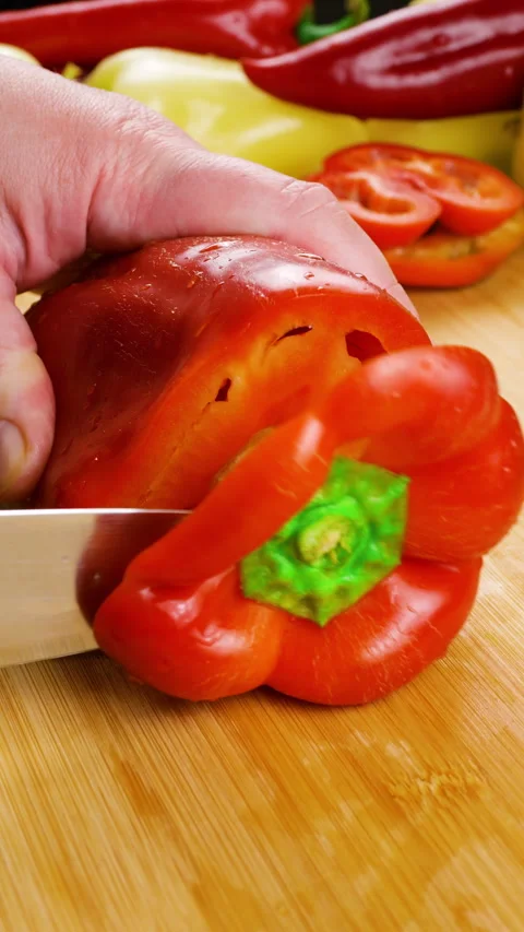 A chef cuts a fresh sweet red bell pepper on a wooden board.  Video stock 341517207