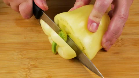 A chef cuts a fresh sweet yellow bell pepper on a wooden board.  库存影片 341525931