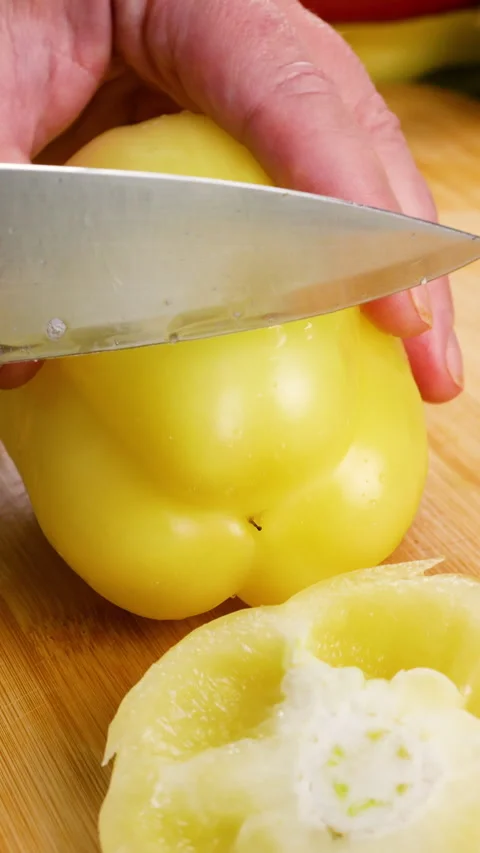 A chef cuts a fresh sweet yellow bell pepper on a wooden board.  库存影片 342283233