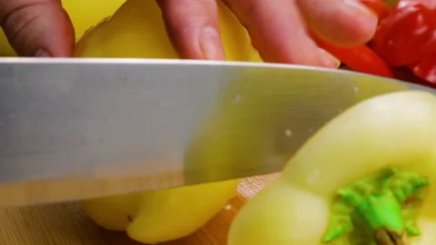 A chef cuts a fresh yellow bell pepper on a wooden chopping board.  Stock Footage 342282864