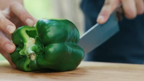 Chef cuts green pepper in half close up of hand and knife full HD video Stock Footage 130774415
