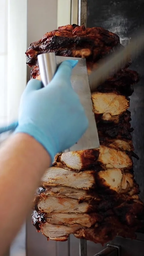 Chef cuts grilled chicken meat from rotating spit and prepares traditional Stock Footage 277410245