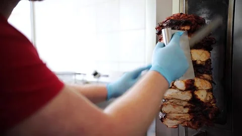 Chef cuts grilled chicken meat from rotating spit and prepares traditional Stock Footage 277410250