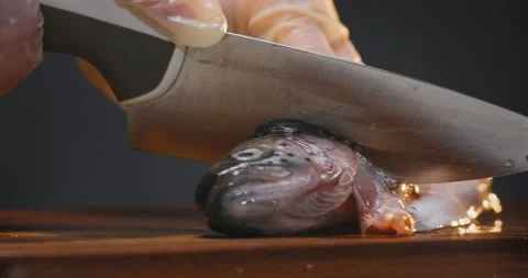 Chef cuts head of red fish with sharp knife on wooden board Stockbeeldmateriaal 149592995