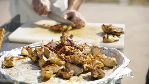 The chef cuts hot meat steaks with the knife and puts pieces of meat on a plate Stock Footage 195287221