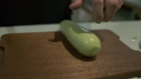 The chef cuts large pieces of zucchini with a knife on a cutting board. Stock Footage 243343875