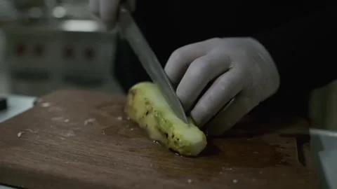 The chef cuts large pieces of zucchini with a knife on a cutting board. Stock Footage 245871394