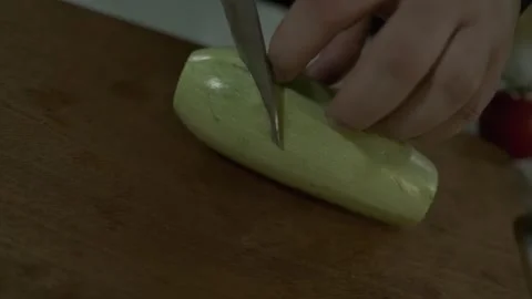 The chef cuts large pieces of zucchini with a knife on a cutting board. Stock Footage 249818173