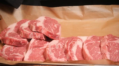Chef cuts meat. Fresh raw meat on metal plate on dark table. Selective focus. Stock Footage 87848444