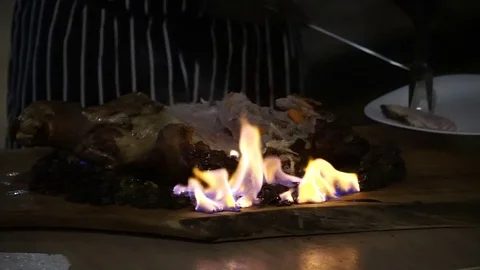 The chef cuts the meat that is still burning Stock Footage 125503760
