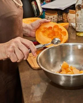 Chef cuts melon balls with special spoon in kitchen Stock Photos