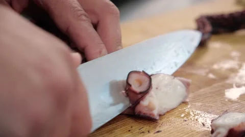 Chef cuts the octopus with a sharp knife.squid tentacles Stock Footage 163971184