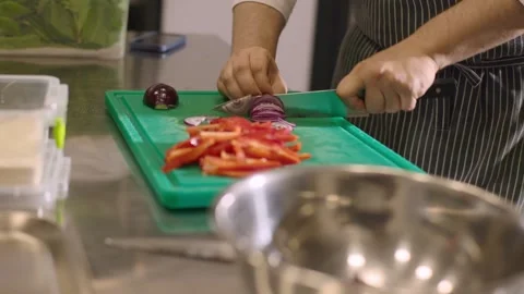 A chef cuts an onion in a restaurant kitchen. Video stock 277131556