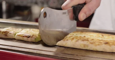 Chef cuts pide with an axe. Traditional Turkish closed pide baked in a Stock Footage 264917147
