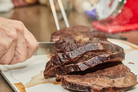Chef cuts piece of beef fried with onions in wine sauce into slices for servi Stock Photos