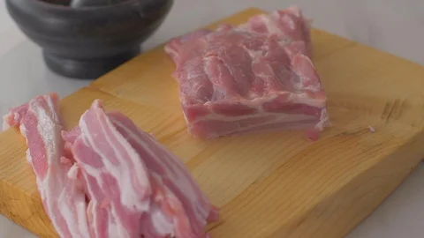 Chef cuts pieces of raw bacon by sharp knife on the wooden board Video stock 111270776
