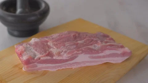 Chef cuts pieces of raw bacon by sharp knife on the wooden board Stock Footage 111271673