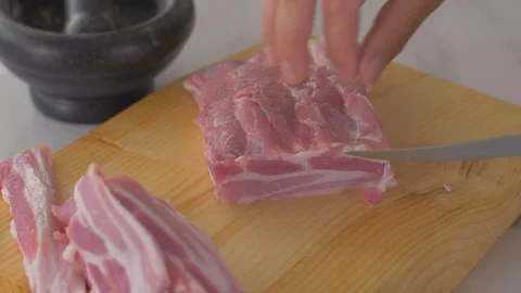 Chef cuts pieces of raw bacon by sharp knife on the wooden board Video stock 111272292