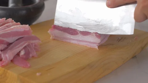Chef cuts pieces of raw bacon by sharp knife on the wooden board Video stock 111272393