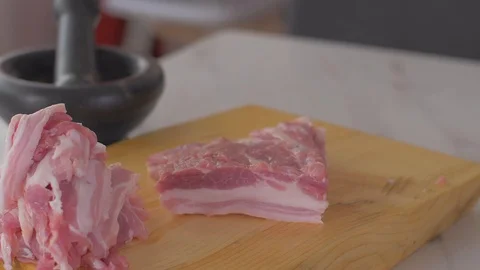 Chef cuts pieces of raw bacon by sharp knife on the wooden board Video stock 111272444