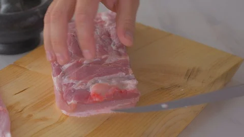Chef cuts pieces of raw bacon by sharp knife on the wooden board Video stock 111272492