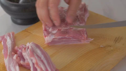 Chef cuts pieces of raw bacon by sharp knife on the wooden board Video stock 111272575