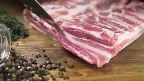 Chef cuts pieces of raw bacon by sharp knife on the wooden board Video stock 143777156
