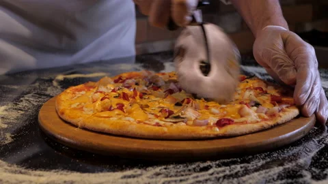 Chef cuts the pizza with prawns into several parts using a special knife. Stock Footage 131333685
