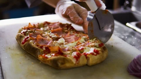 The chef cuts the pizza into several slices with a special knife for cutting Vídeo Stock 103203620
