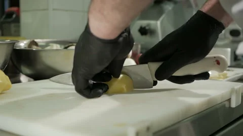 The chef cuts the potatoes in black gloves. Cooking a dish Stock-Footage 106335730