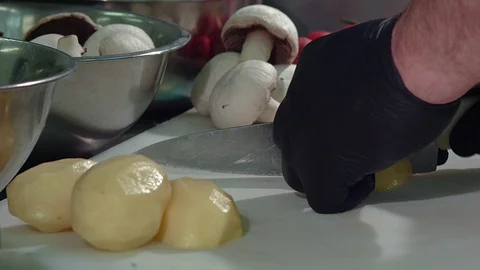 The chef cuts the potatoes in black gloves. Cooking a dish Stock Footage 106436830