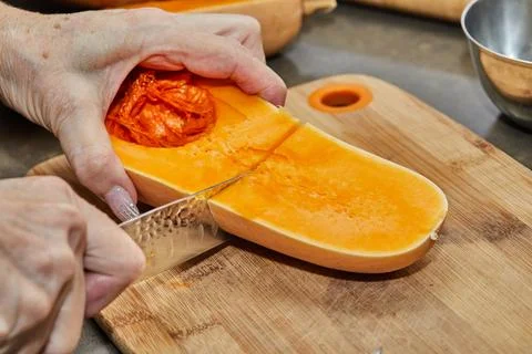Chef cuts pumpkin in the shape of pear on wooden board in the home kitchen Stock Photos