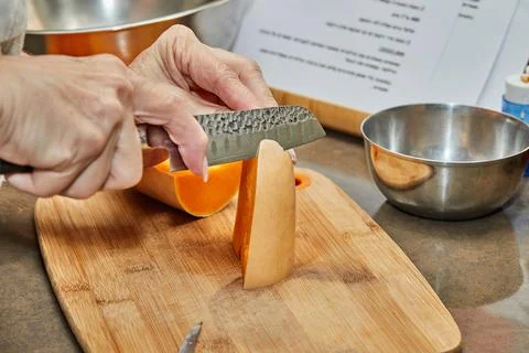 Chef cuts pumpkin in the shape of pear on wooden board in the home kitchen Stock-Fotos