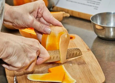 Chef cuts pumpkin in the shape of pear on wooden board in the home kitchen Stock Photos