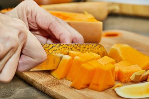 Chef cuts pumpkin in the shape of pear on wooden board in the home kitchen Stock Photos