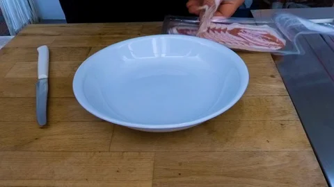 Chef cuts the raw bacon into a white dish to fry it in extra-virgin olive oil Vídeo Stock 101155876