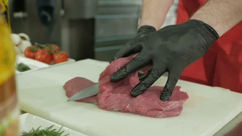 The chef cuts the raw beef with a knife in black gloves. Stock Footage 106254015